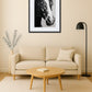 Tableau cheval noir et blanc style dessin au crayon au-dessus d’un canapé avec table basse ronde en bois et lampe moderne