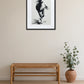 Tableau cheval encre de Chine noir et blanc au-dessus d’un banc en rotin avec plante dans un intérieur minimaliste