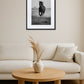 Tableau photographie cheval noir et blanc au-dessus d’un canapé beige avec table ronde en bois et vase décoratif