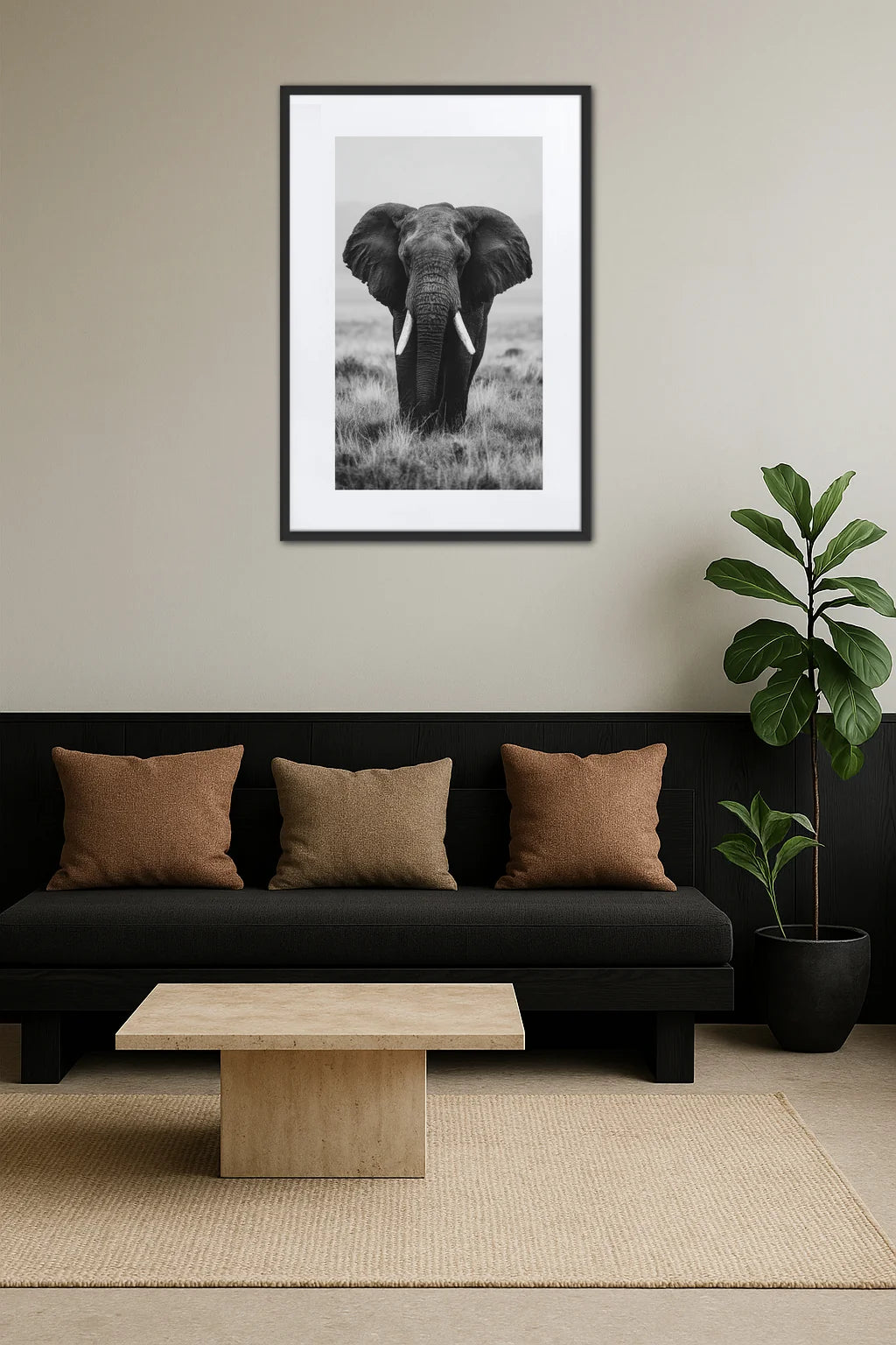 Tableau éléphant noir et blanc de face dans la savane au-dessus d’un canapé noir avec coussins et plante verte