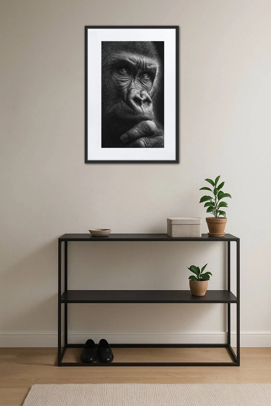 tableau gorille noir et blanc au dessus d’une console noire avec plantes