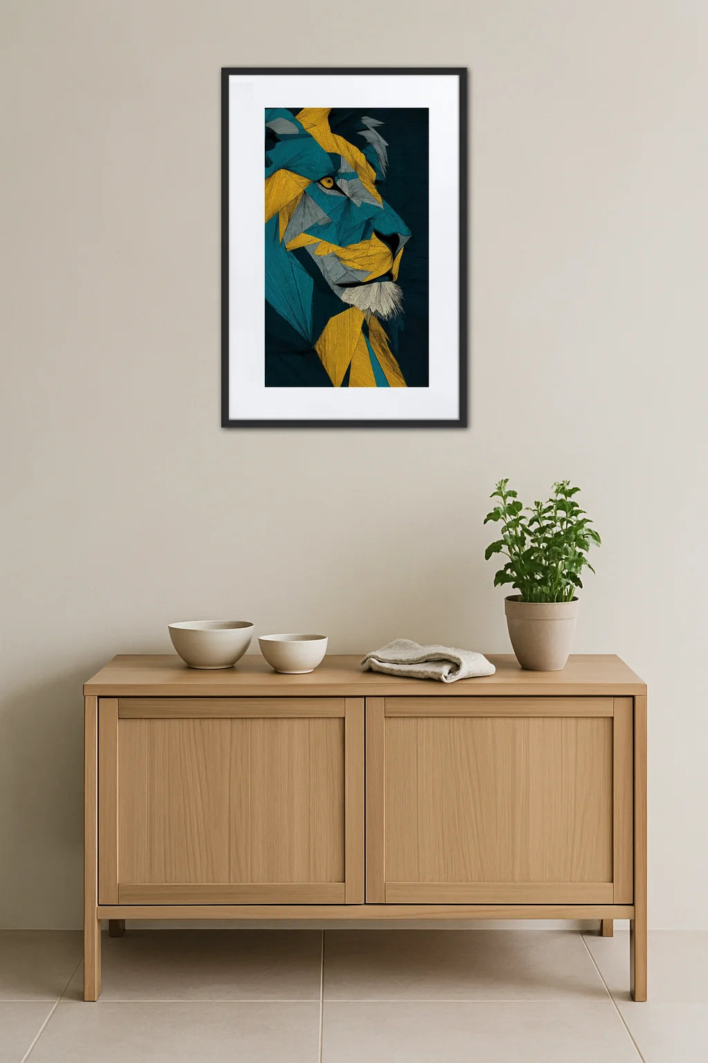 Tableau lion abstrait géométrique accroché au-dessus d’un meuble en bois avec bols, linge plié et plante en pot