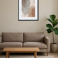 Tableau minimaliste éléphant abstrait accroché au-dessus d’un canapé beige avec table basse en bois et plante verte dans un salon épuré